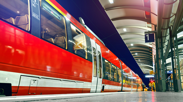 Ein roter Zug steht an einem Bahnhof