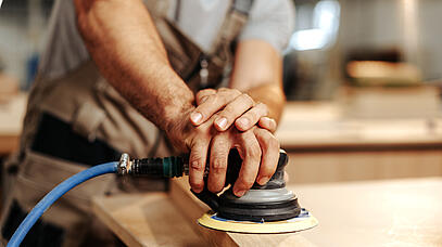 Mann, der mit einer Schleifmaschine Holz schleift