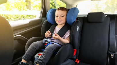 Ein lachendes Kind sitzt in einem Kindersitz auf dem Rücksitz eines Autos