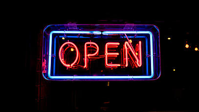 Ein Neonschild zeigt in rot und blau die Aufschrift: Open.