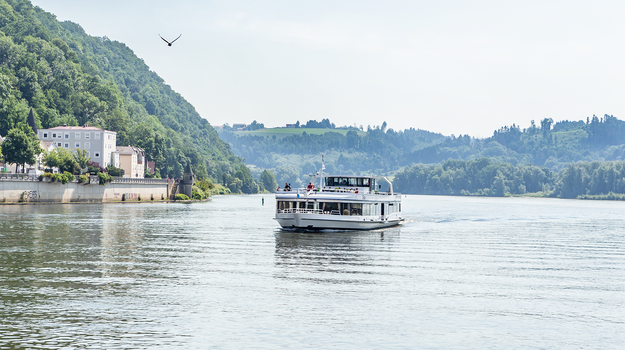 Ein weißes Ausflugsschiff auf einem großen Fluss