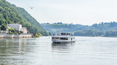 Ein weißes Ausflugsschiff auf einem großen Fluss