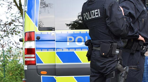Polizeiauto vor dem von hinten ein Polizist zu sehen ist
