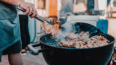 Eine Person grillt Fleisch auf einem Grill 