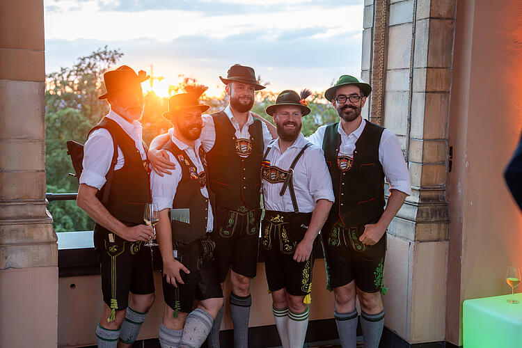 Männer in Tracht stehen im Arkadengang des Landtags.