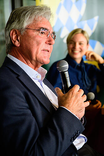 Joe Kaeser spricht in ein Mikrofon, im Hintergrund Katharina Schulze