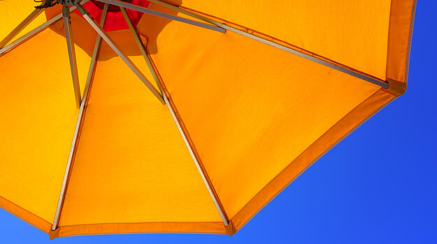 Gelber Sonnenschirm vor blauem Himmel