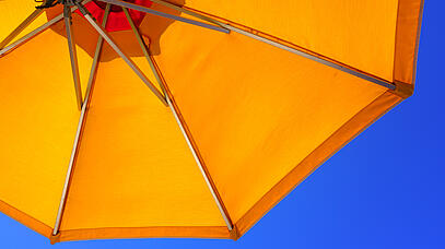 Gelber Sonnenschirm vor blauem Himmel