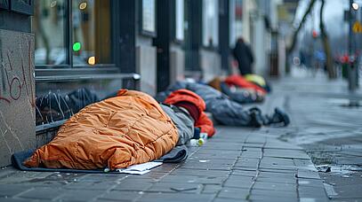 Obdachloser in Schlafsack am Straßenrand