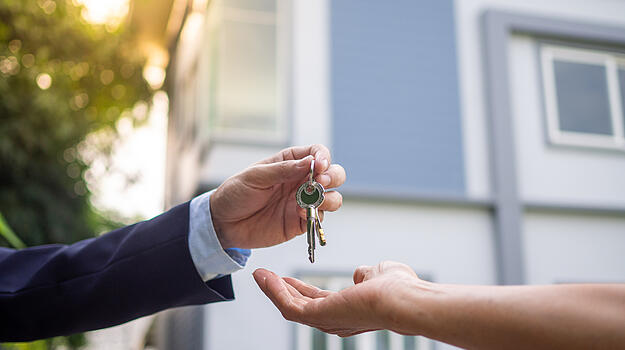 Eine Hand gibt einer anderen Hand einen Haustürschlüssel