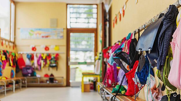 Eine Garderobe mit vielen Kinderrucksäcken und Kinderjacken.