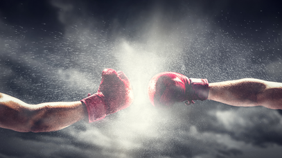 Zwei Arme in Boxhandschuhen schießen aufeinander zu 