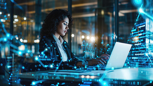 Eine Frau, die an einem Laptop arbeitet, überlagrt von digitalen Grafiken.