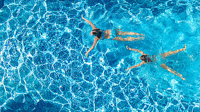 Zwei junge Frauen beim Schwimmen im Schwimmbad. Von oben fotografiert.