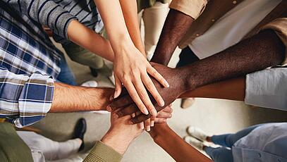Hände unterschiedlicher Hautfarben zusammengelegt