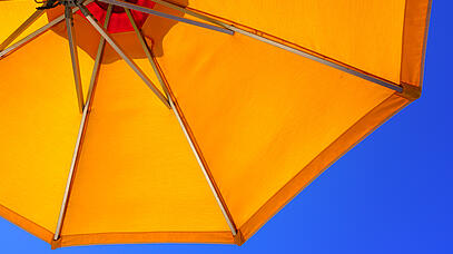 Gelber Sonnenschirm vor blauem Himmel