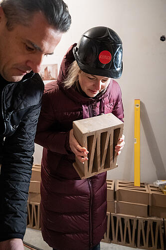 Katharina Schulze, MdL, hält einen Ziegelstein in der Hand.