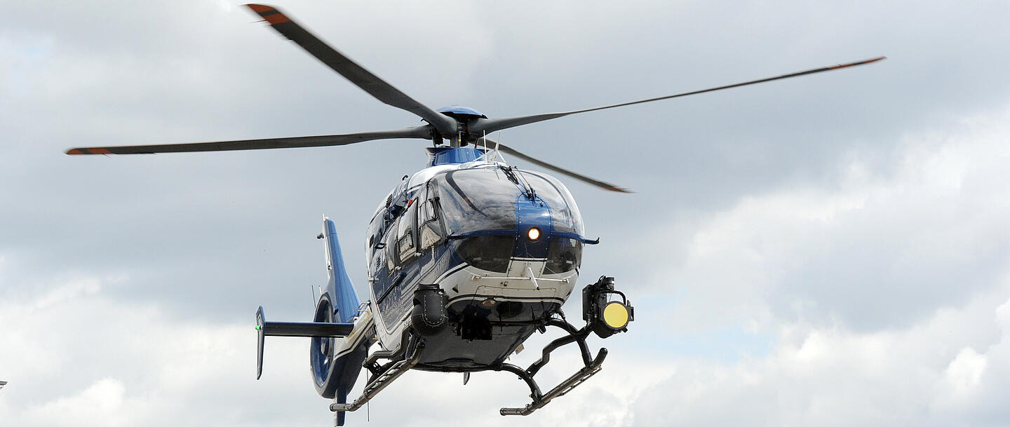Ein Polizeihubschrauber schwebt vor bewölktem Himmel