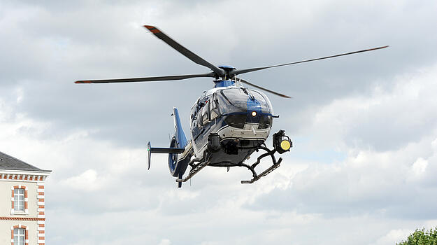 Ein Polizeihubschrauber schwebt vor bewölktem Himmel