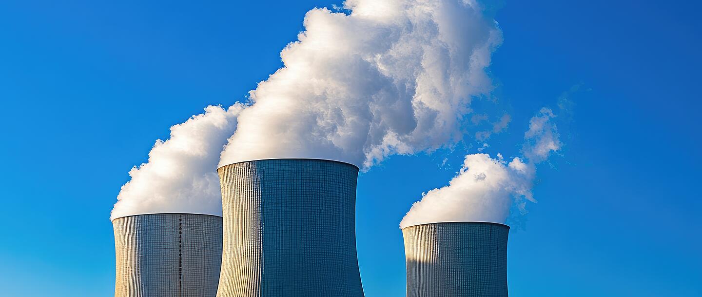 Aus drei großen Kühltürmen steigt weißer Dampf aus.