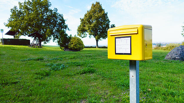 Gelber Briefkasten im Hintergrund grüne ländliche Landschaft