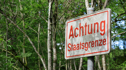 Auf einem Schild steht in roter Farbe: Achtung Staatsgrenze