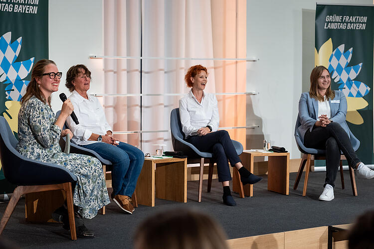 Julia Post, MdL, Sissy Raith, Prof. Dr. Susanne Burger und Mareike Miller sitzen auf der Bühne für eine Podiumsdiskussion. Julia Post moderiert das Gespräch.
