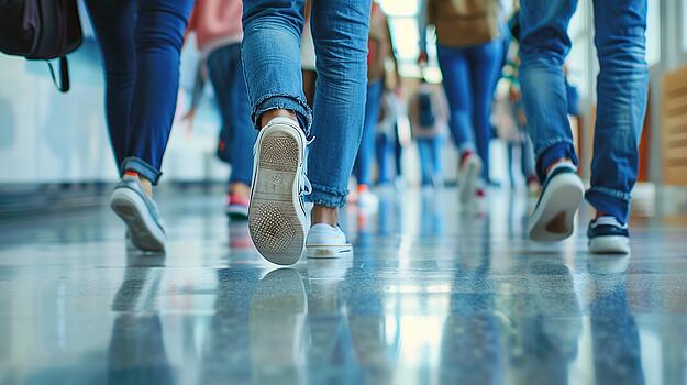 Schuhe und Beine von Kindern und Jugendlichen, die über den Flur in einer Schule gehen