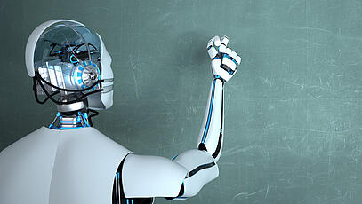 Roboter schreibt mit weißer Kreide auf grüne Tafel.