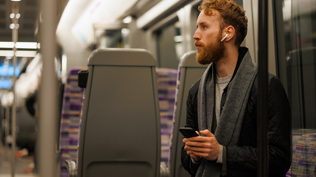 Hinter einem Mann mit Handy füllen Sitze in Zweierreihen das Bild aus