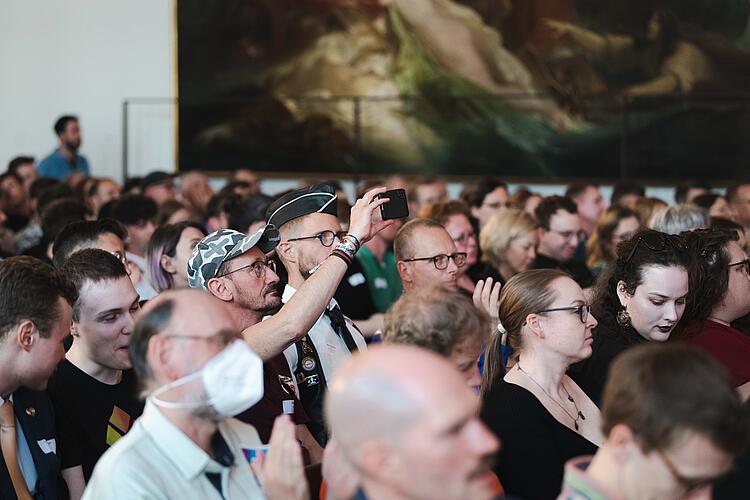Menschen sitzen im Saal und beobachten die Veranstaltung.